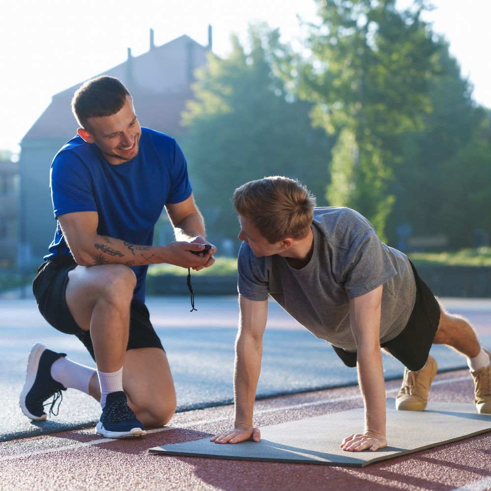 Two men exercising outdoors on a track with trees in the background