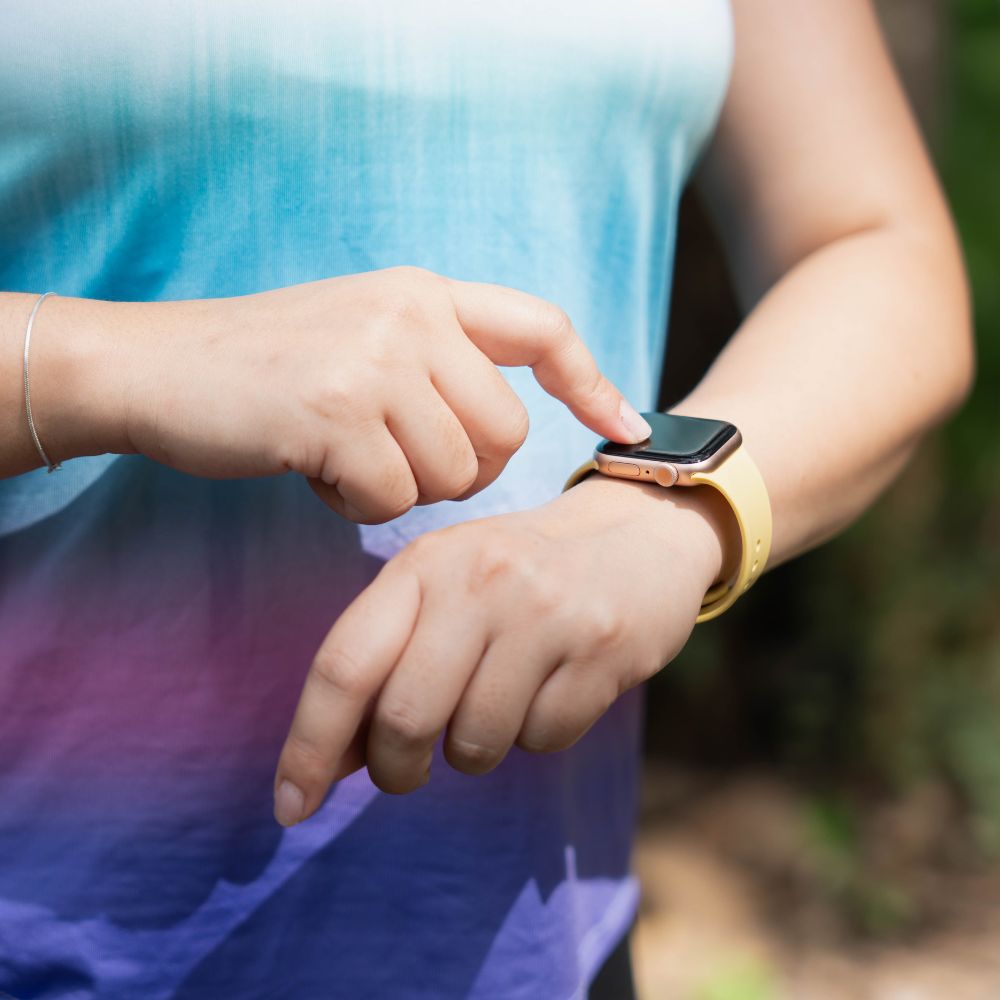 Person using a smartwatch with a blurred natural background